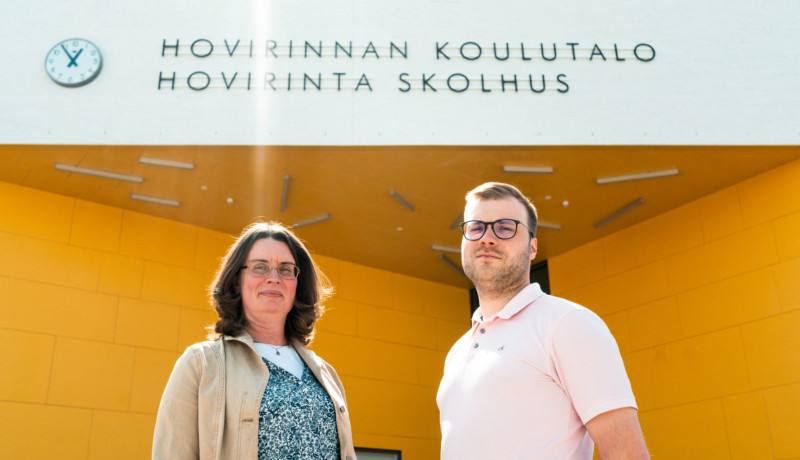 Två personer framför en byggnad.