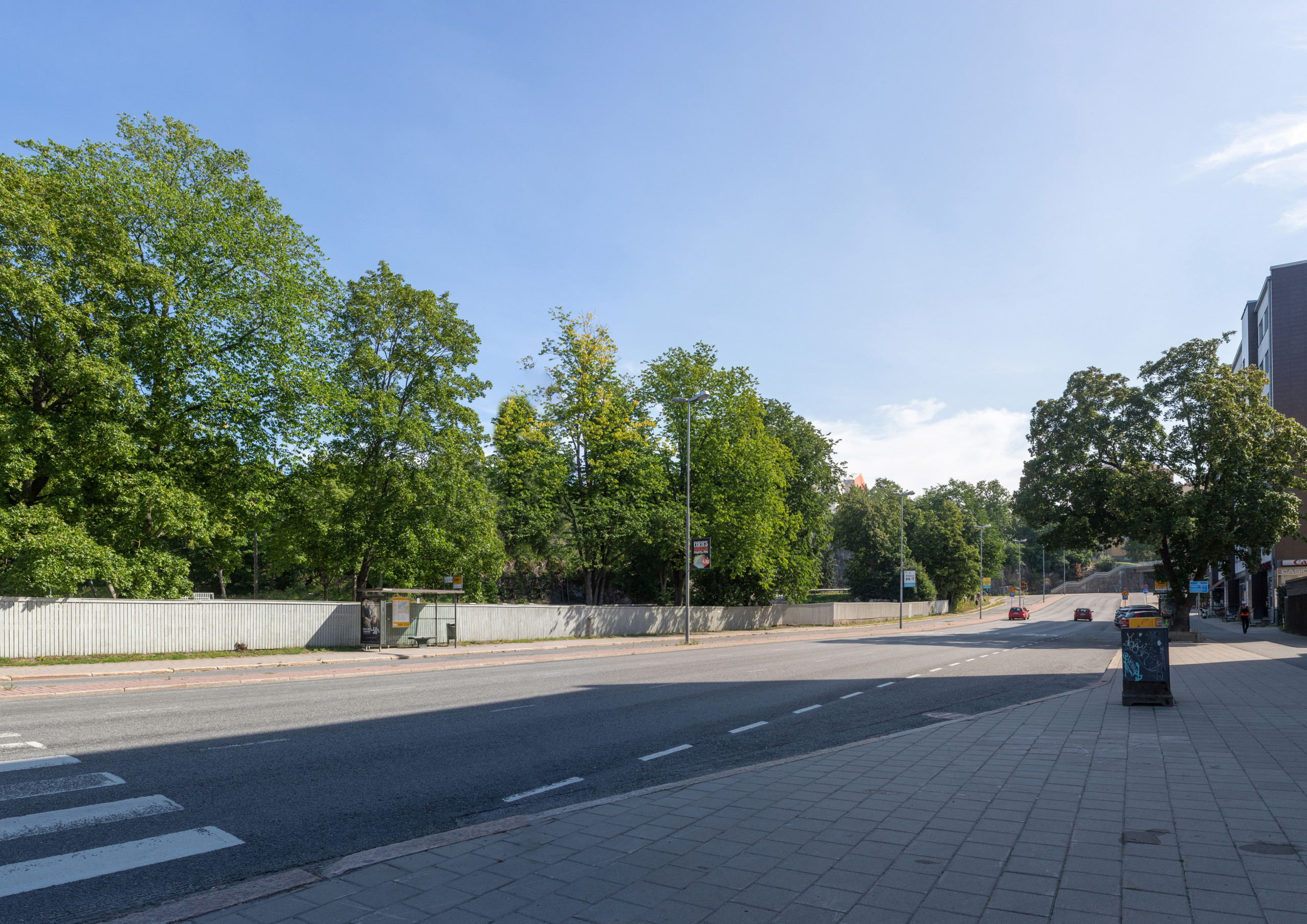 Stadsgata med gröna träd i bakgrunden