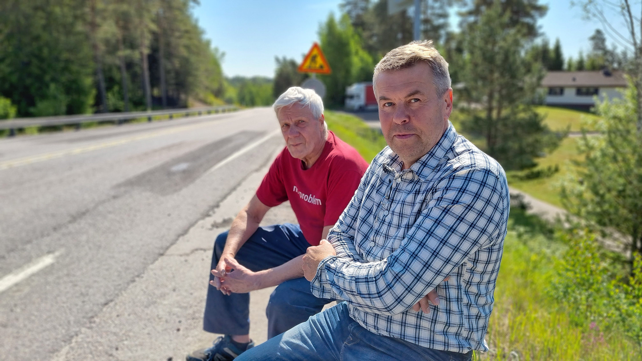 Två män sitter vid landsväg.