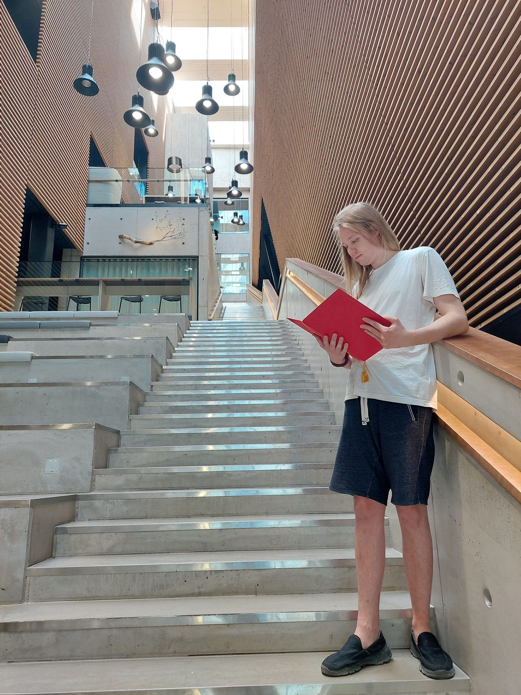 Ung man står i en trappa i Åbo Akademi och tittar när i sitt betyg, han är nyligen utexaminerad.