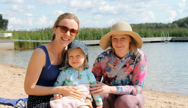 Två kvinnor med ett barn på strand.