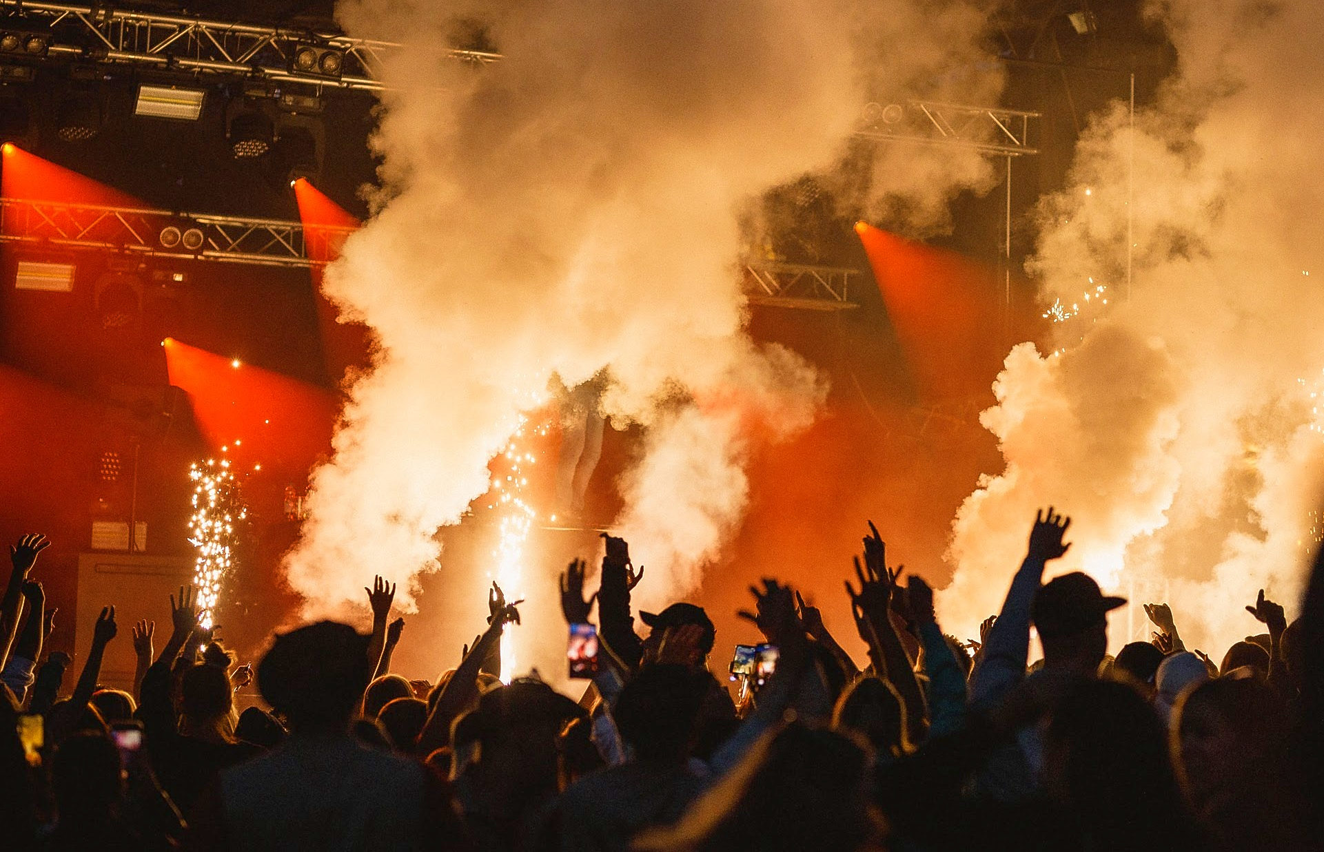 Festivalpublik framför upplyst scen där rökmaskiner bolmar ut rökmoln