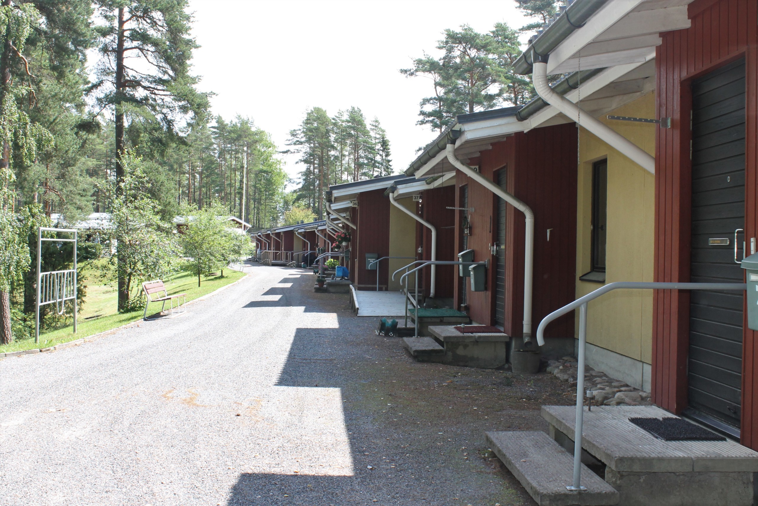Rött radhus fotat utomhus. Flera dörrar på rad och man skymtar även en gräsmatta.