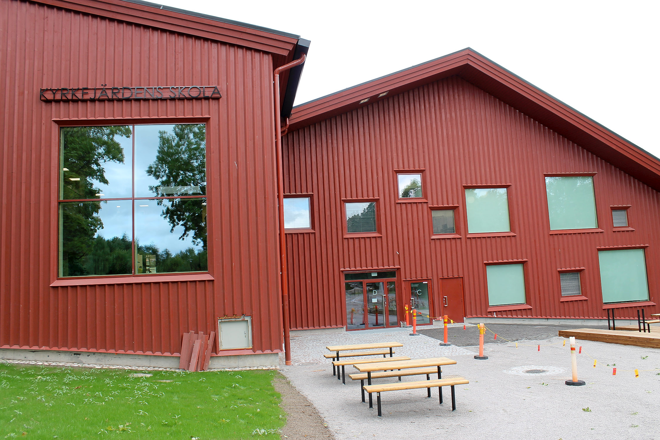 En stor röd skola fotad utifrån. Skolan finns i Ingå och byggnaden har flera fönster i olika storlekar och är byggd av trä.