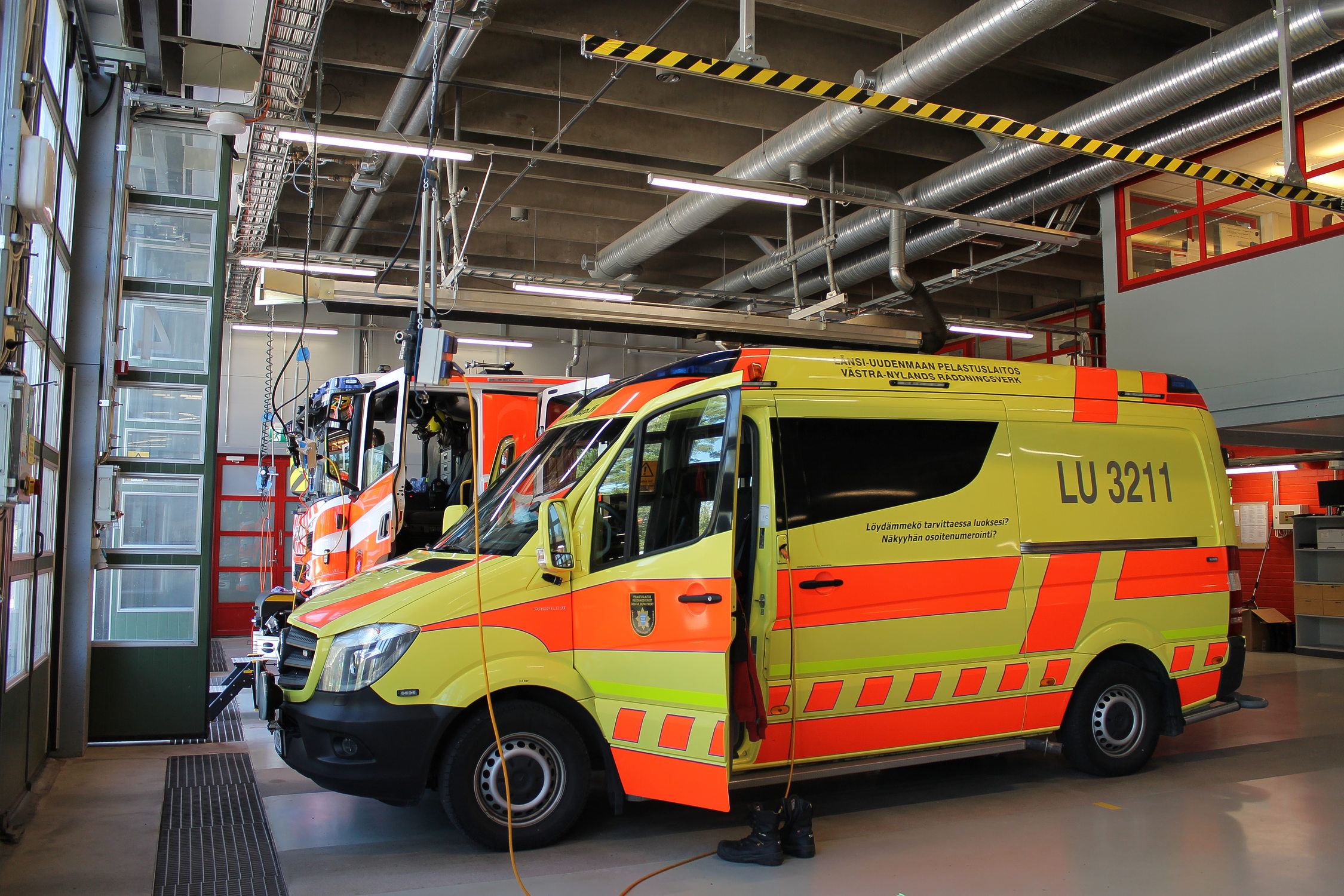 Bild tagen inne i Ekenäs brandstation. En ambulans är längst fram i bilden och i bakgrunden ser man en brandbil.