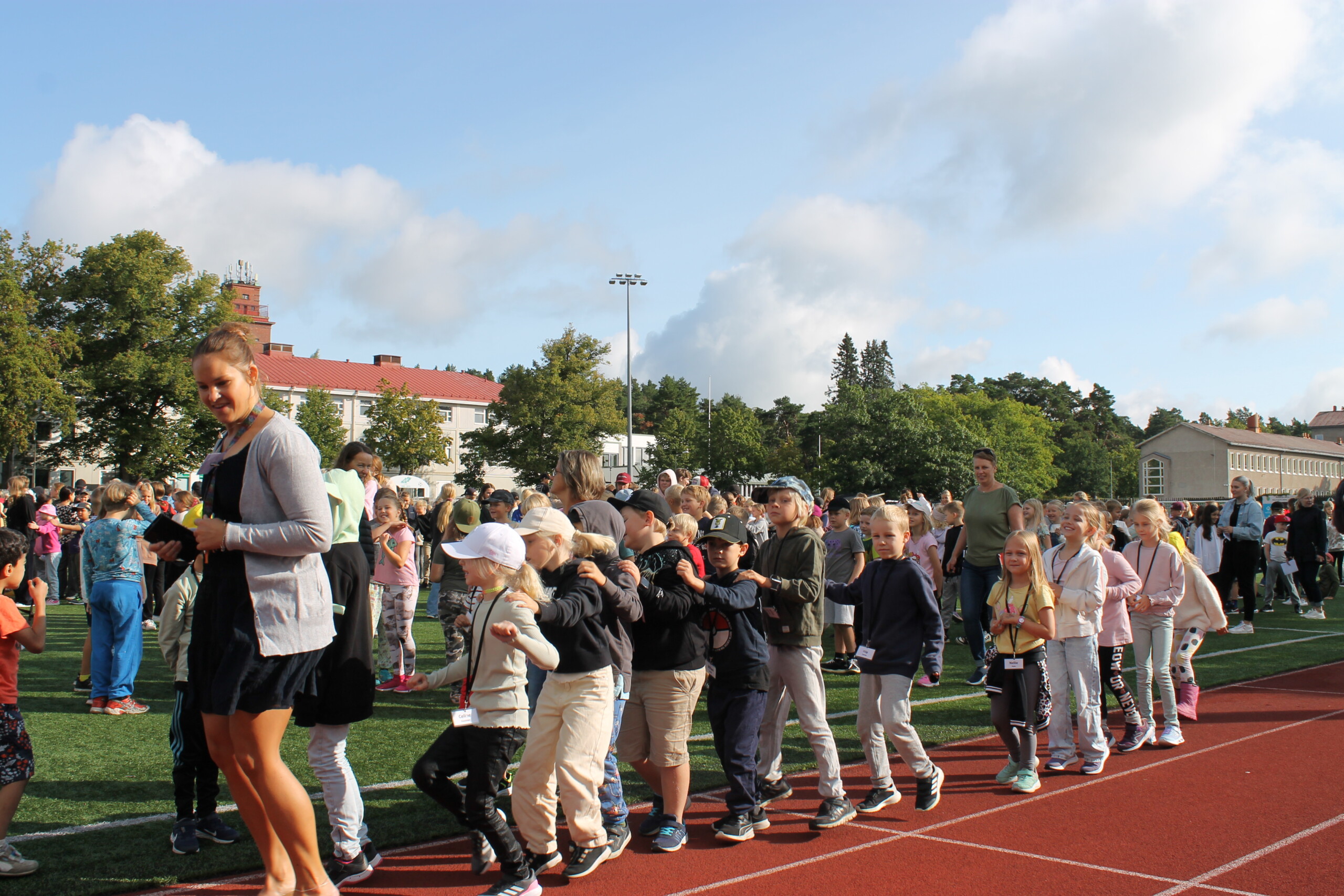 Elever och lärare dansar letkajenkka tillsammans utomhus i Ekenäs. Eleverna har just utlyst skolfred.