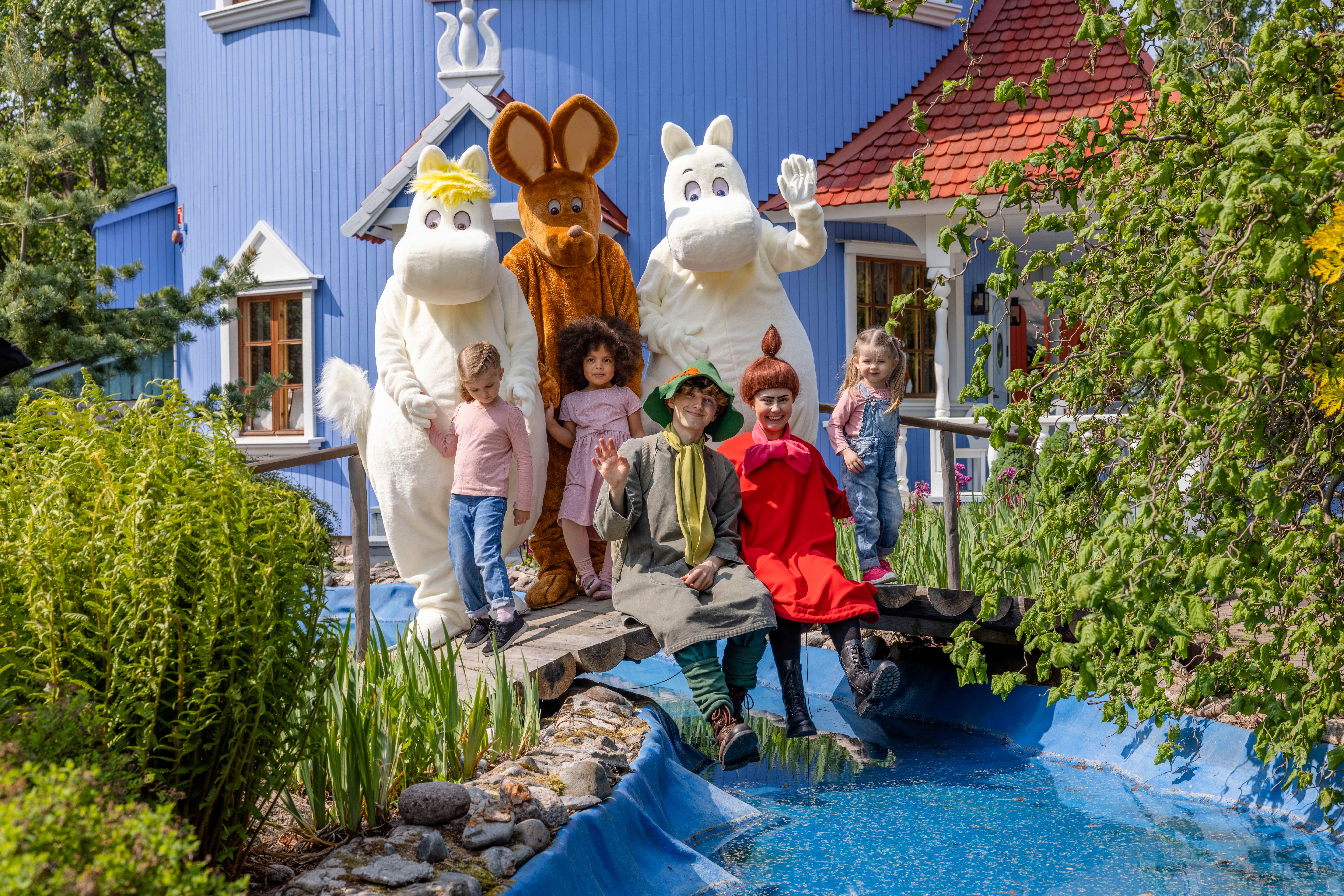 Muminfigurer utanför ett blått hus