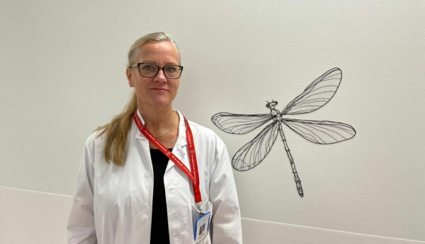 En läkare med en slända som ett konstverk i bakgrunden.