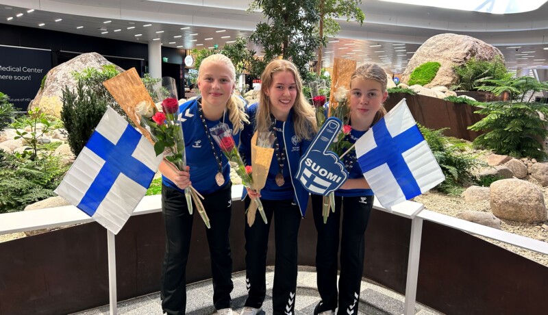 tre tjejer med blommor och finska flaggor