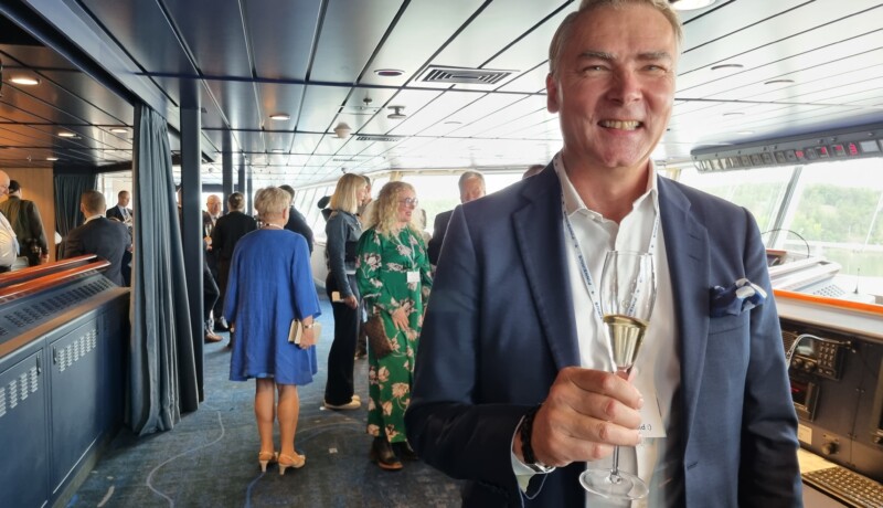 Kostymklädd, leende man håller i ett skumvinsglas
