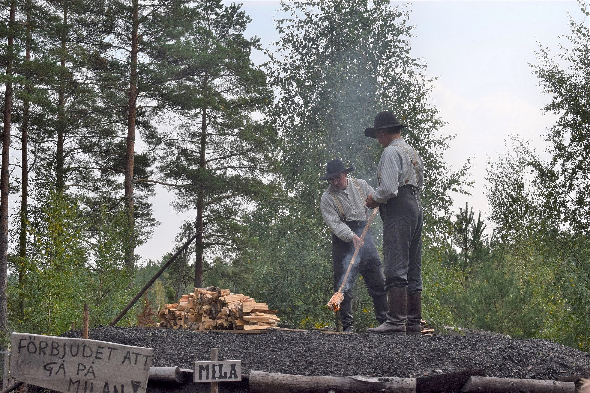 Kolargubbar i tidsenlig klädsel tänder kolmila.