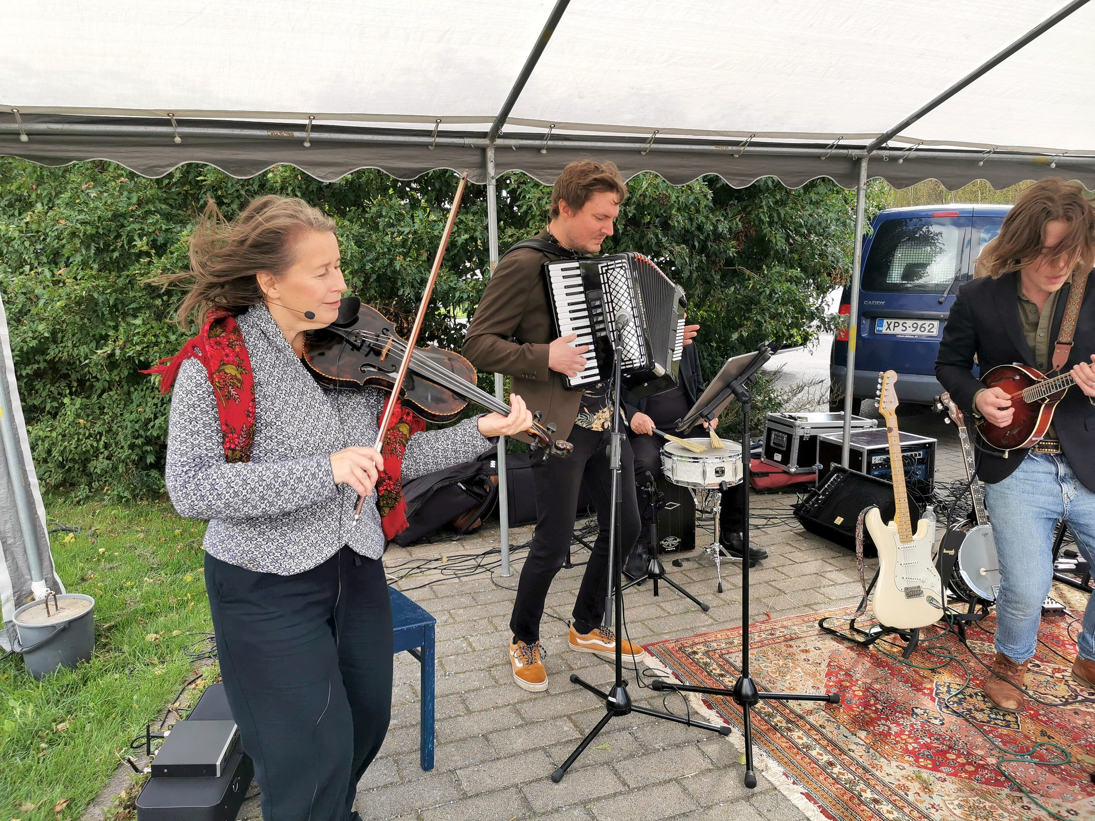 Tre personer som spelar musik med fiol, dragspel och banjo.