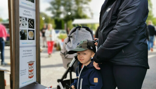 Kvinna med barn och barnvagn på marknad.