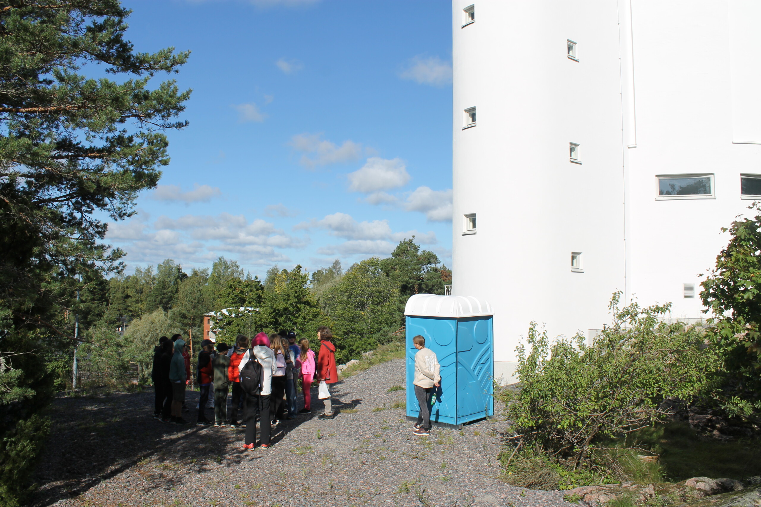 Fotat på håll en grupp elever utanför vattentornet i Karis. Där en kvinna berättar om stjärnor och planeter för eleverna.