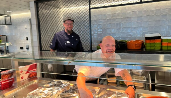Två män i kockkläder förbereder folieöverdragna serveringskärl