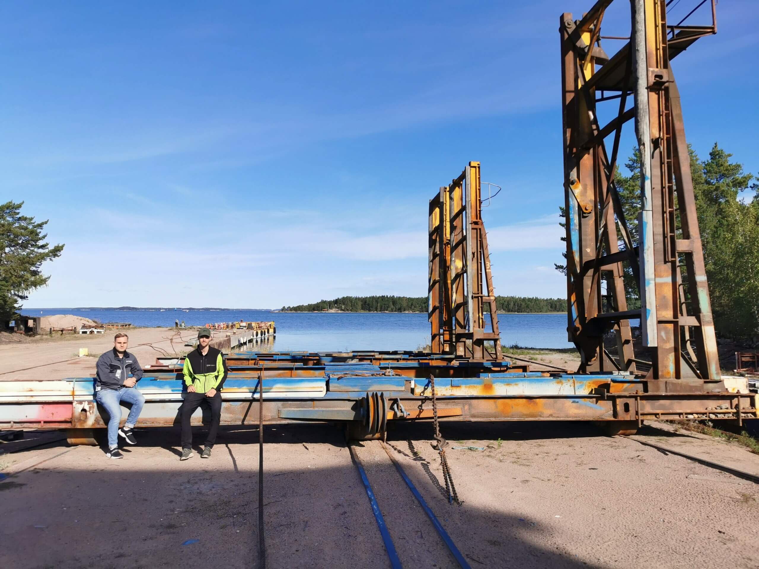 Två män sitter på slipvagn på varv.