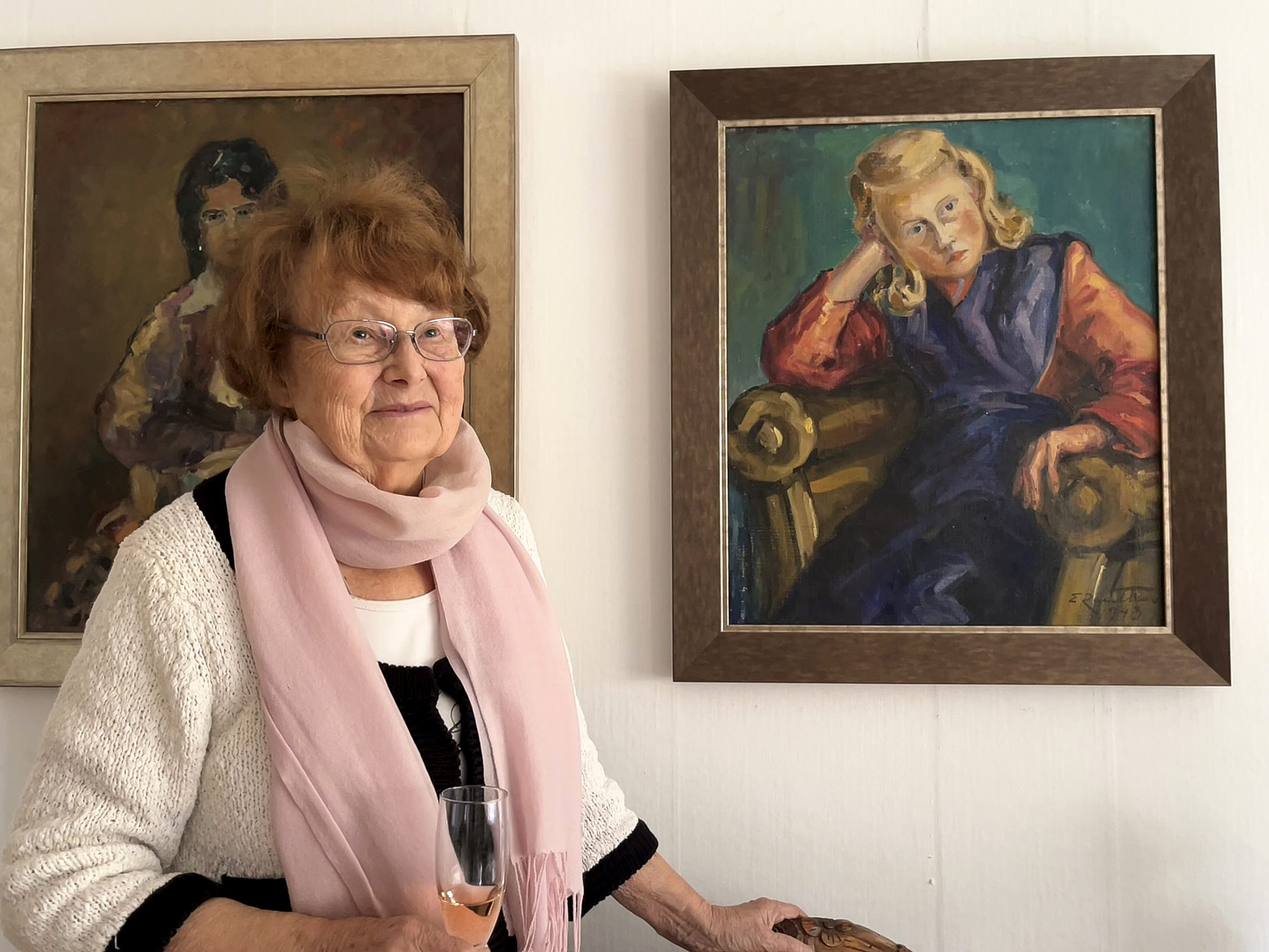 Kvinna framför ett porträtt av henne som tioåring