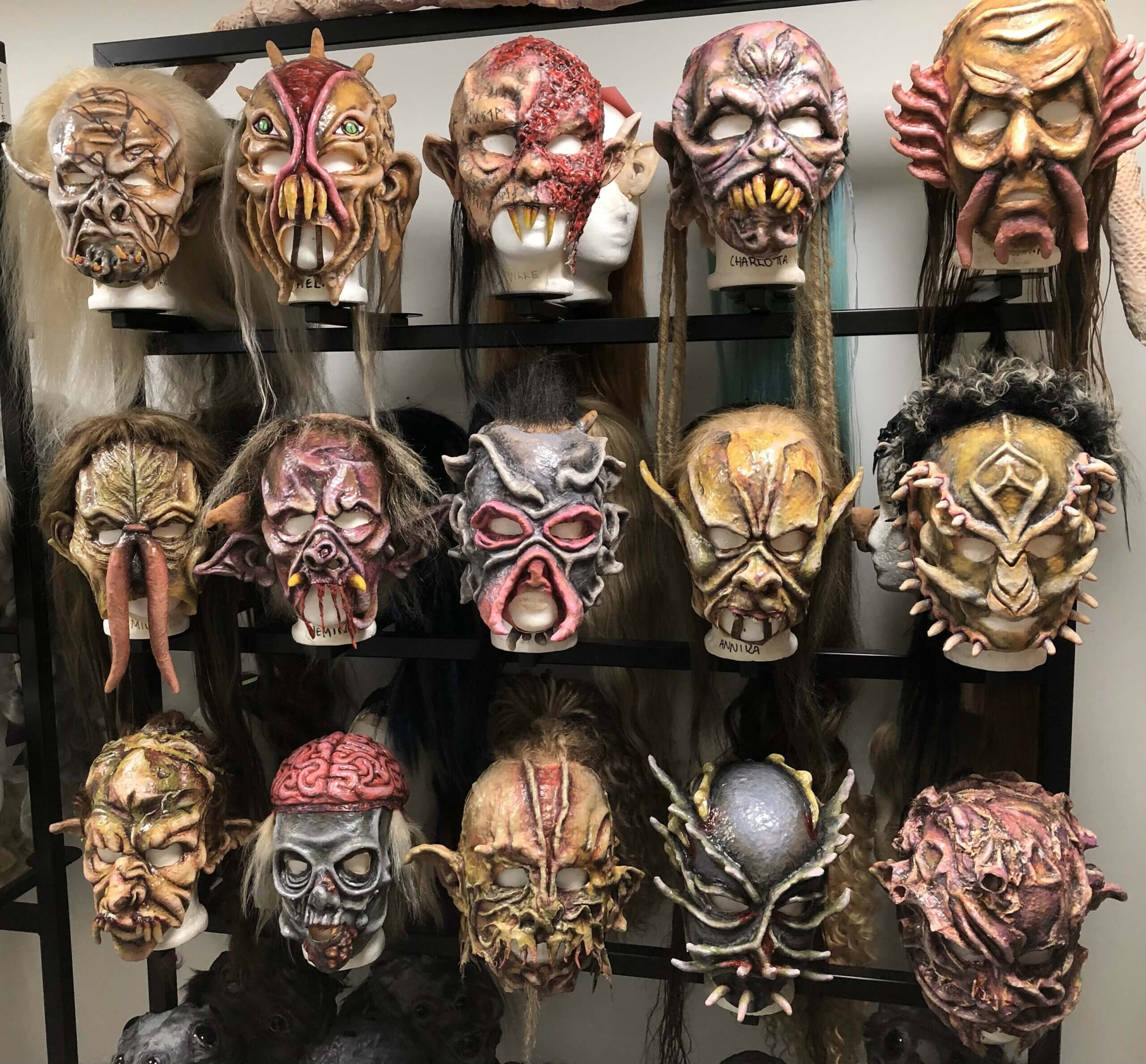 Skrämmande masker i rad på en vägg.