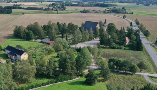 Landskapsvy över gles bosättning, en stenkyrka och åkrar