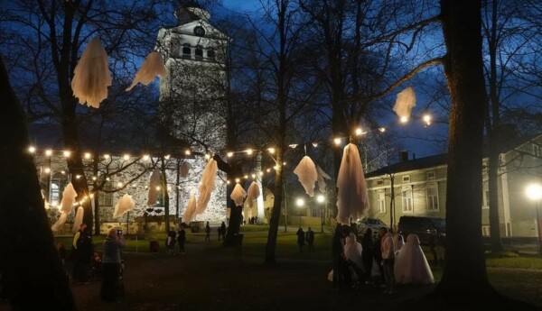 Kväll vid Ekenäs kyrka, spöken hänger från träden och några människor syns på bilden.