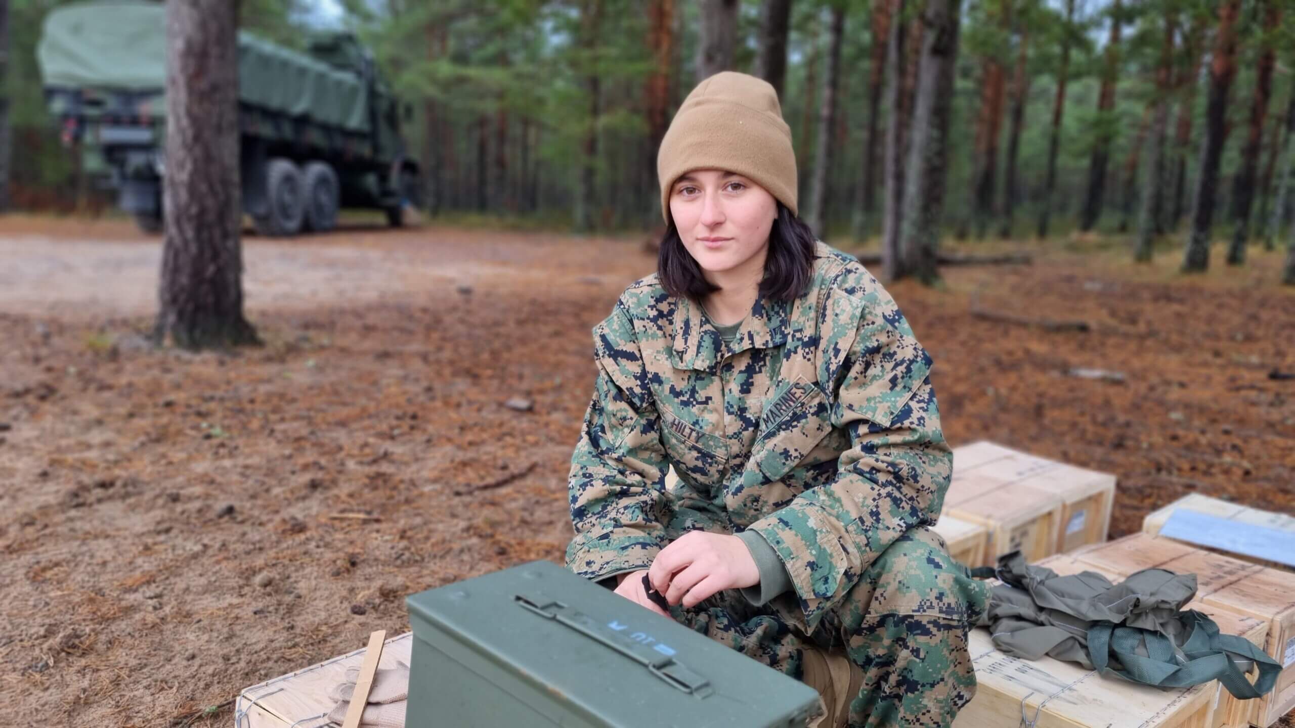 Ung kvinnlig soldat bland ammunitionslådor.
