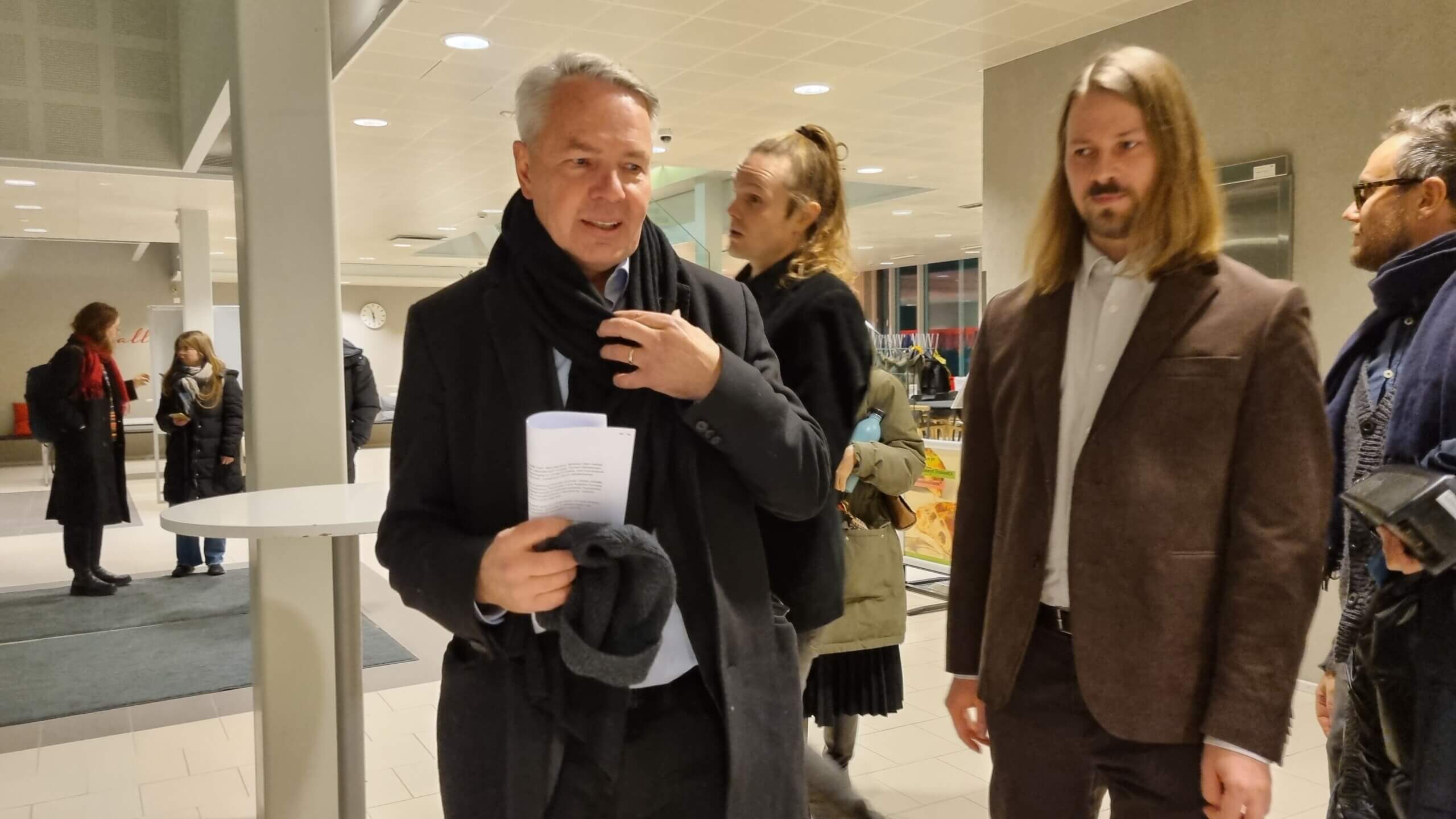 man med ytterrock i aula