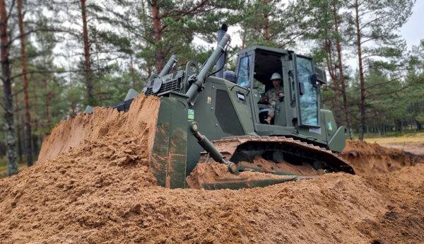 En amerikansk bulldozer bygger skydd för fordon i terrängen.