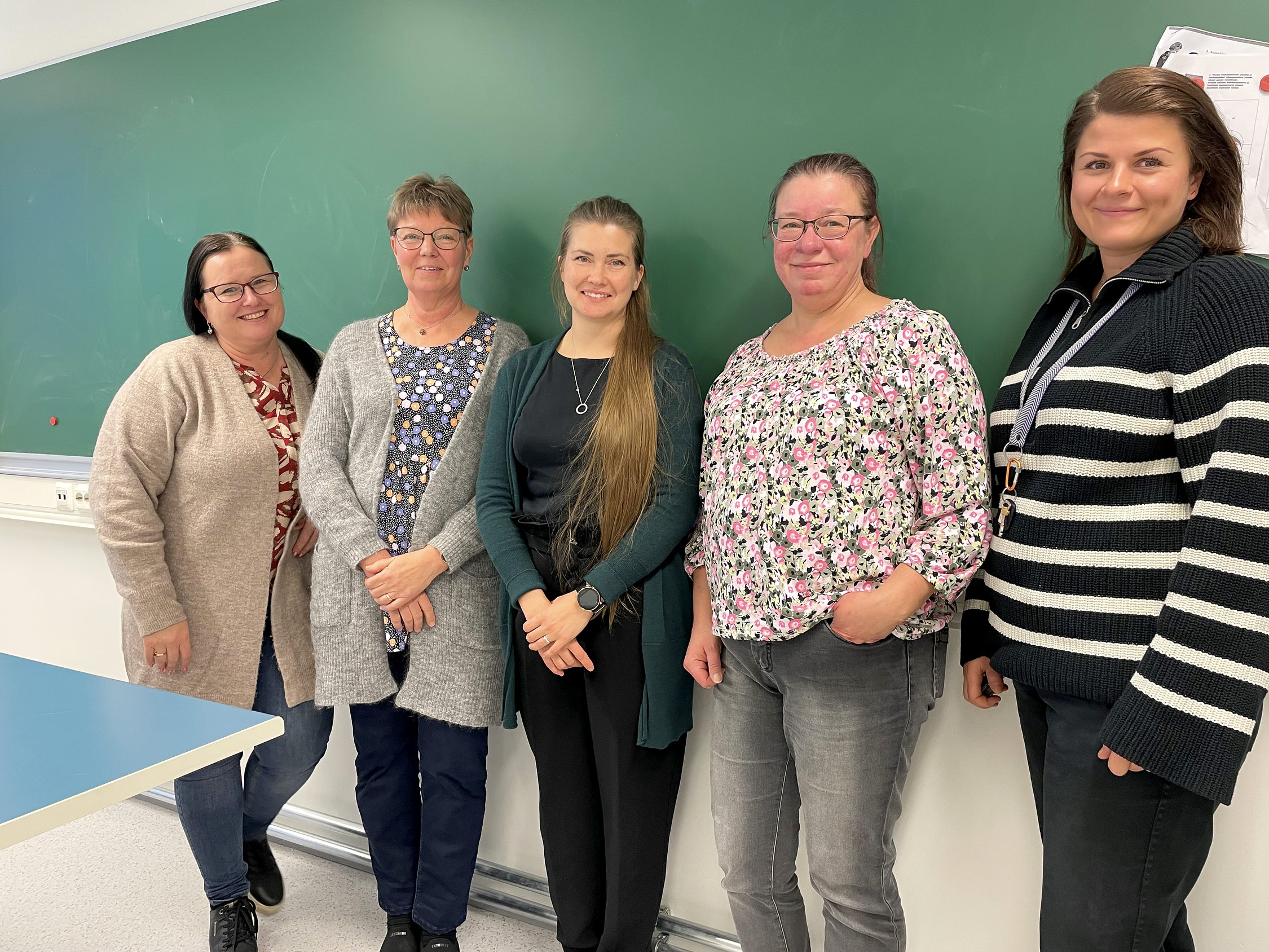 Fem kvinnor i rad vid en skoltavla