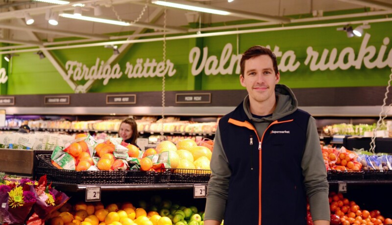 en man står vid en fruktdisk i en matbutik