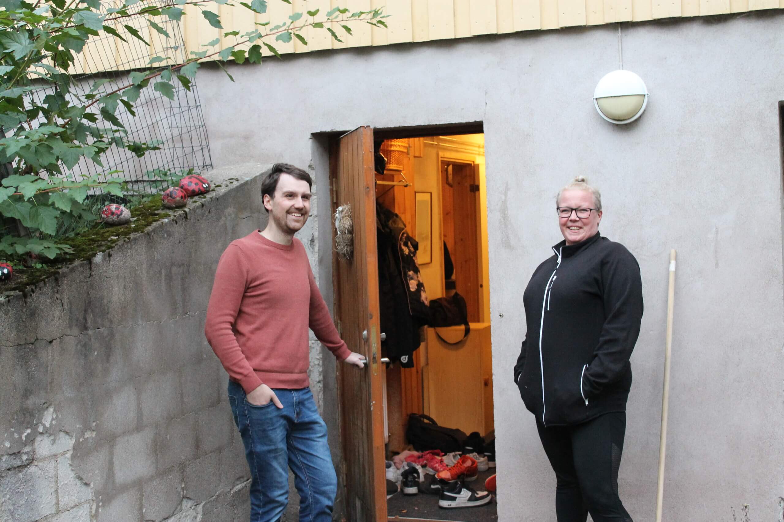 En man håller upp en dörr till en källare i ett hus. En kvinna står bredvid honom och ler. Dörren mannen öppnat är till den nya ungdomsgården i Tenala.