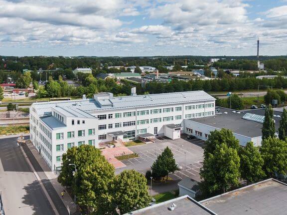En vit skolbyggnad fotad från luften.