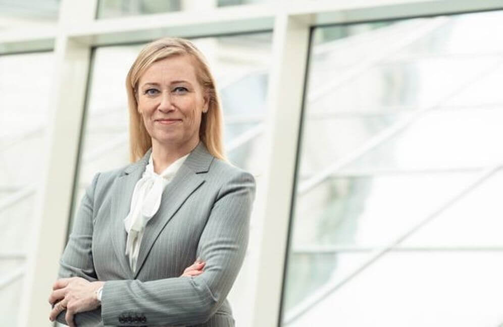 kvinna i grå kostym står med armarna i kors
