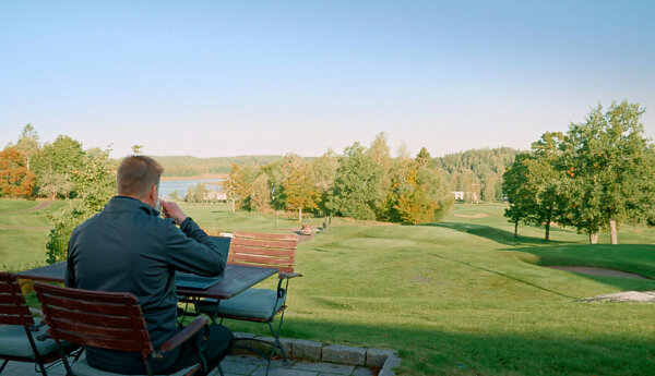 Man jobbar på dator på golfbana.