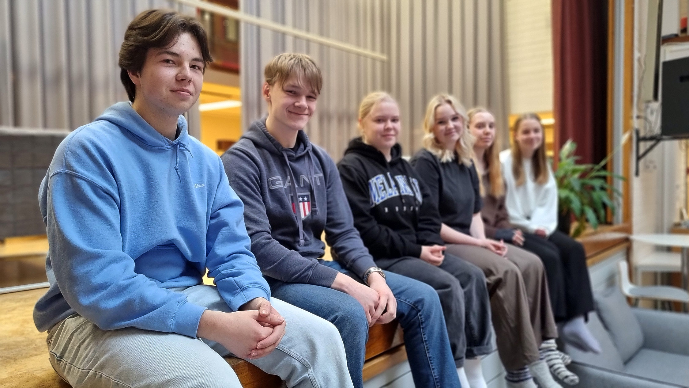 Elever sitter på rad på kanten av en scen.