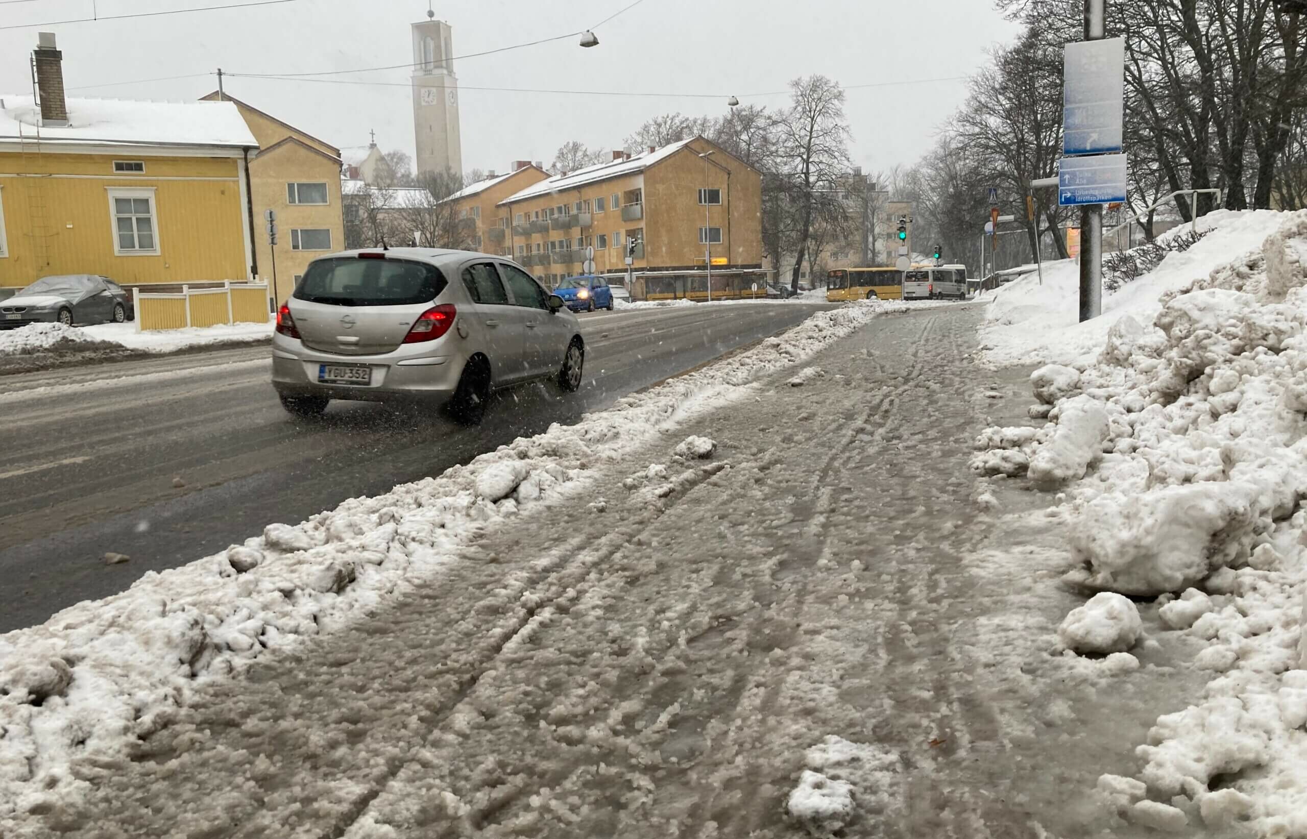 Slaskig trottoar och silverfärgad bil som kör förbi