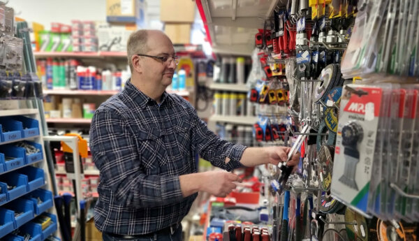 Man vid hylla med verktyg i butik.