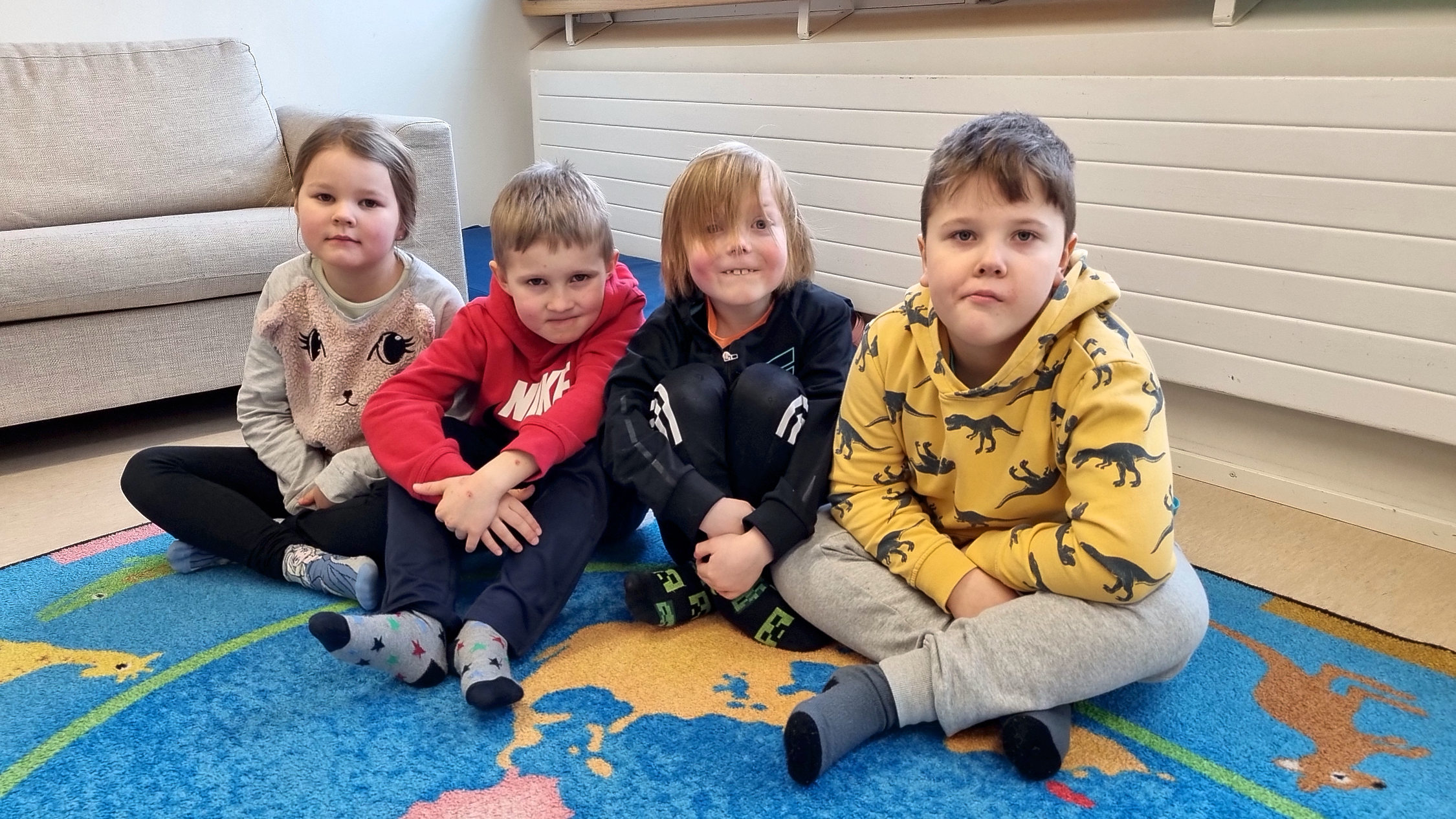 Fyra förskolebarn på golvet.