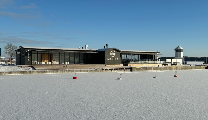 Restaurangbyggnad på en pir i vinterlandskap.
