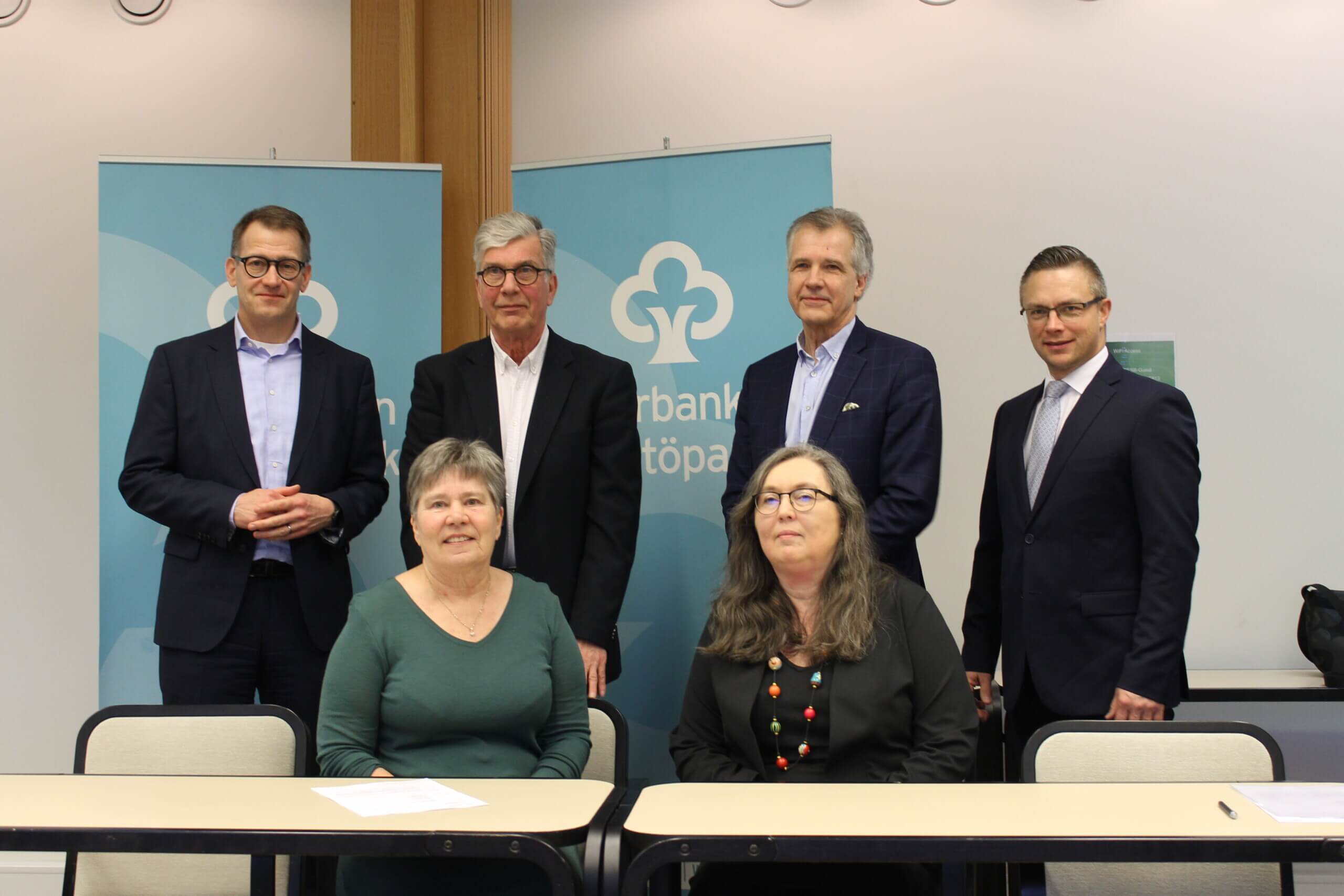 Gruppfoto av några män och kvinnor inomhus i Ekenäs. De är representanter från Ekenäs Sparbank, bankens stiftelse och Raseborgs stad som samlats för att underteckna ett avtal gällande bankens stiftelses bidrag till renoveringen av Centrumplan i Ekenäs.