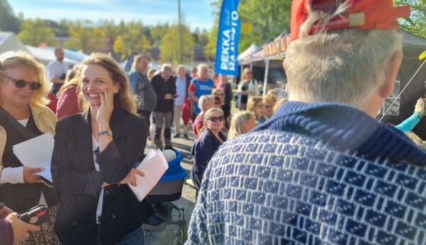 Kvinna bland besökare på solig marknad.