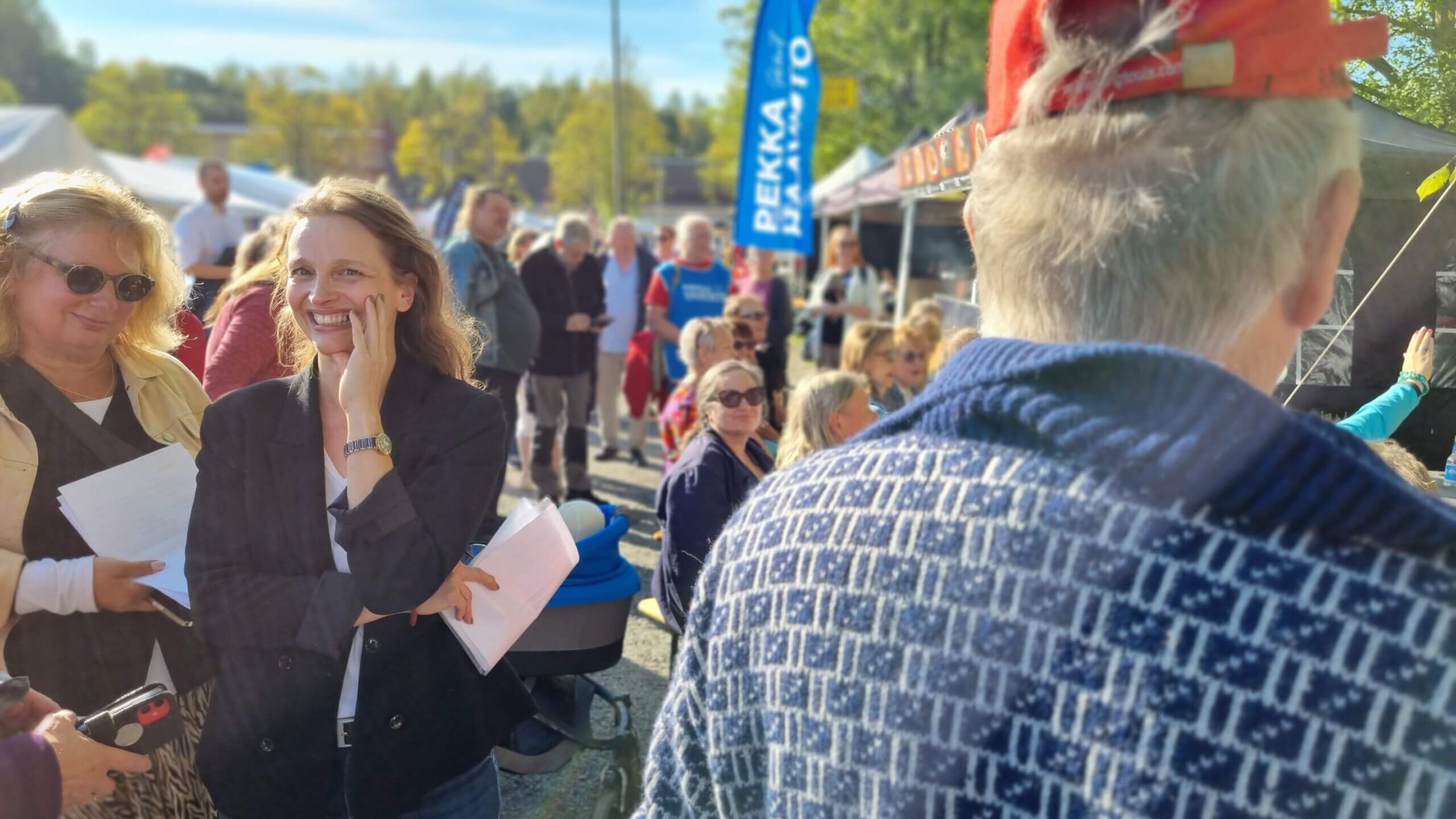 Kvinna bland besökare på solig marknad.