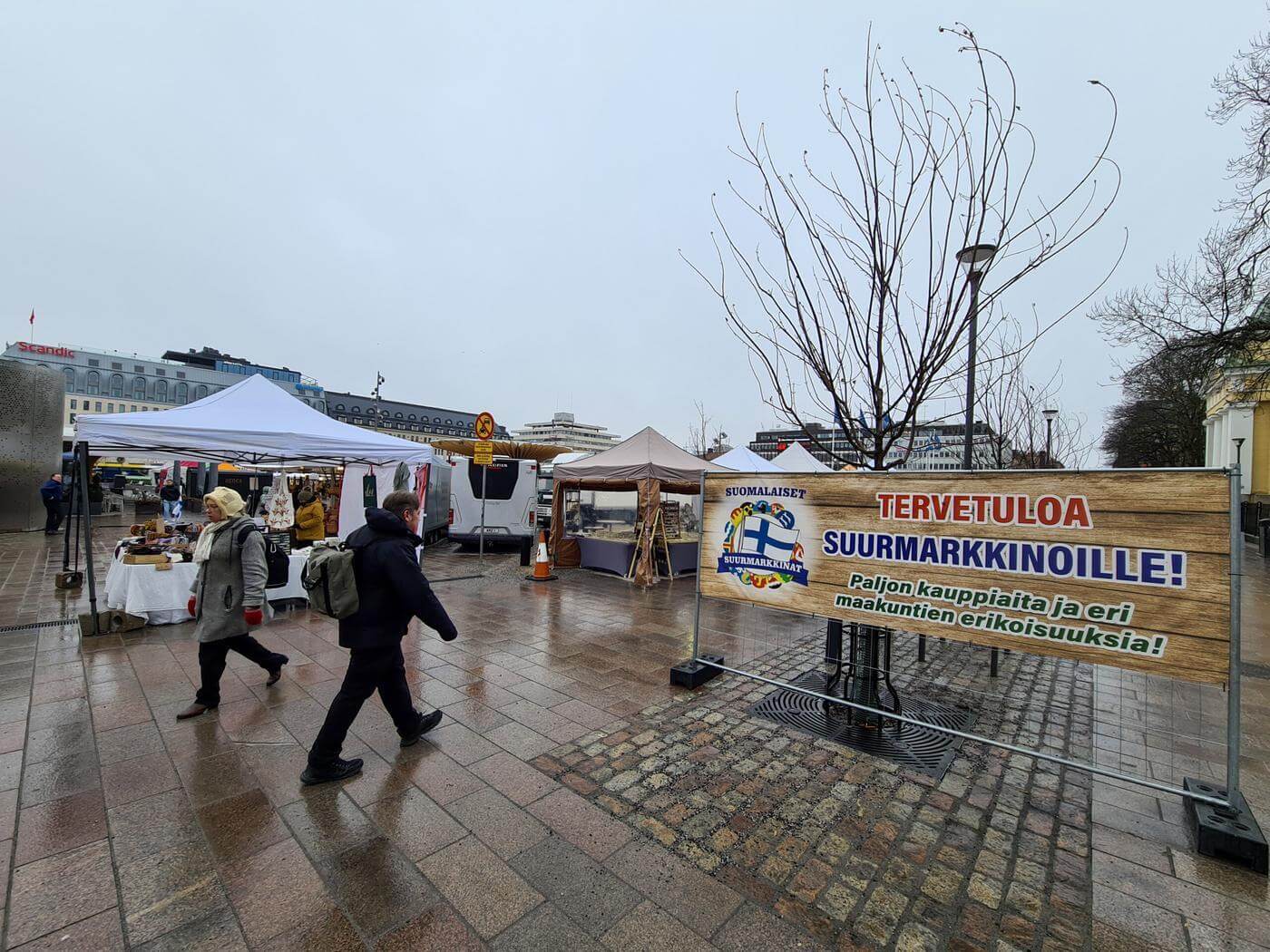 Vy mot ett torg fyllt av marknadsstånd en grå och regnig dag