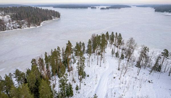 Flygbild av snötäckt udde vid sjö.