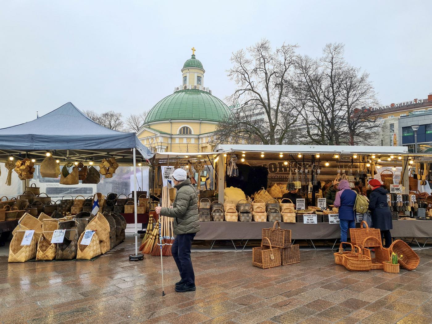 Två stora marknadsstånd som säljer korgar och andra hantverk. I bakgrunden tornar sig en kupolformad kyrka.