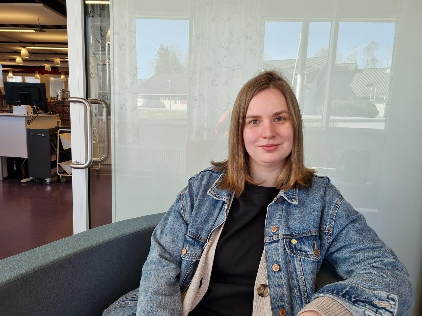 en kvinna i jeansjacka sitter i en stol