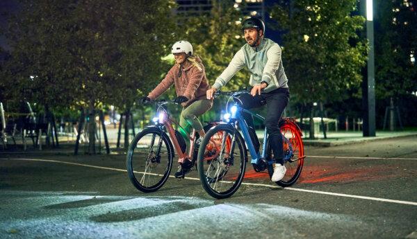 Man och kvinna på elcyklar i mörker.