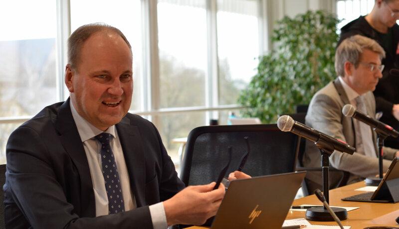 en man sitter vid ett mötesbord framför en dator
