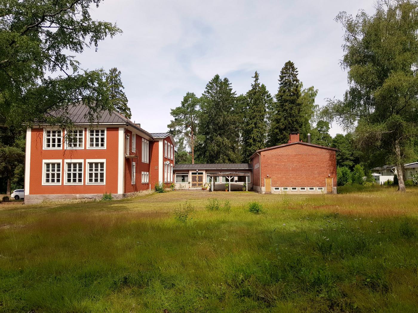 Gammalt skolhus i rött med flera byggnadskroppar