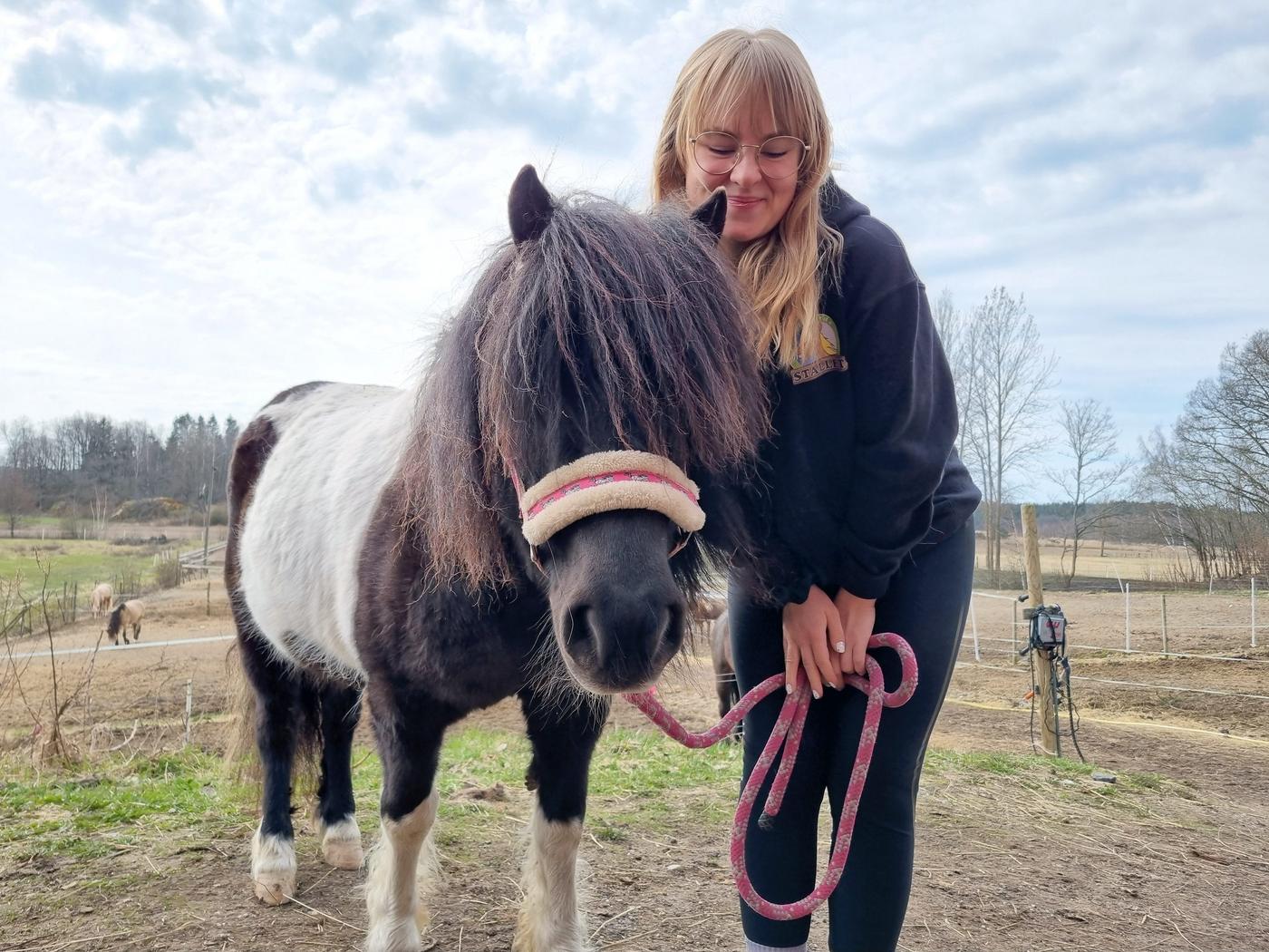 en kvinna med en svartvit ponny