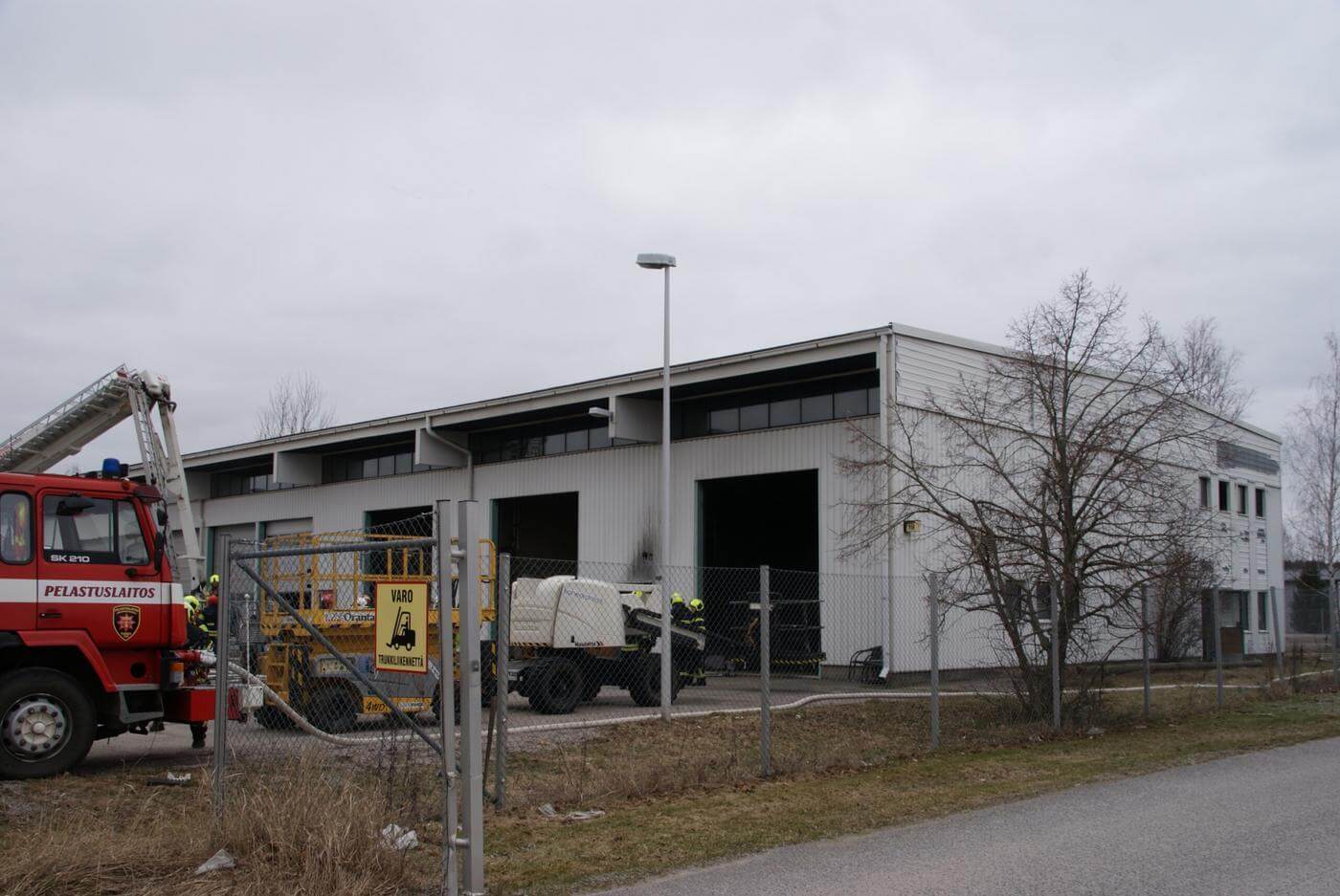 Brandbil och brandmän utanför industrihall.